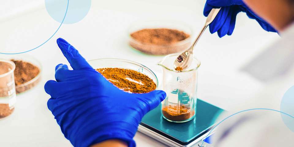 A lab technician scooping spices into a beaker