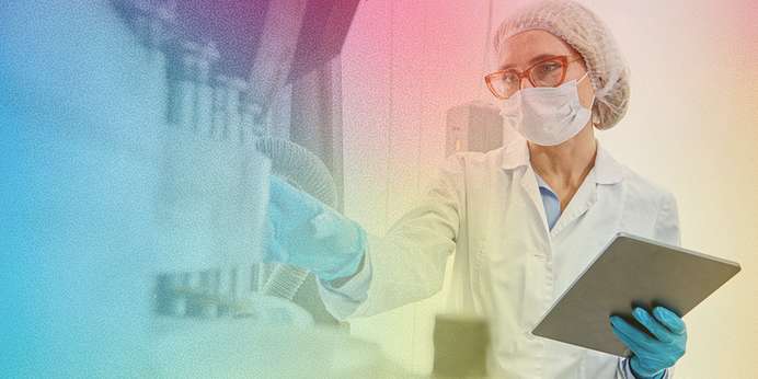 A lab technician working while holding a tablet