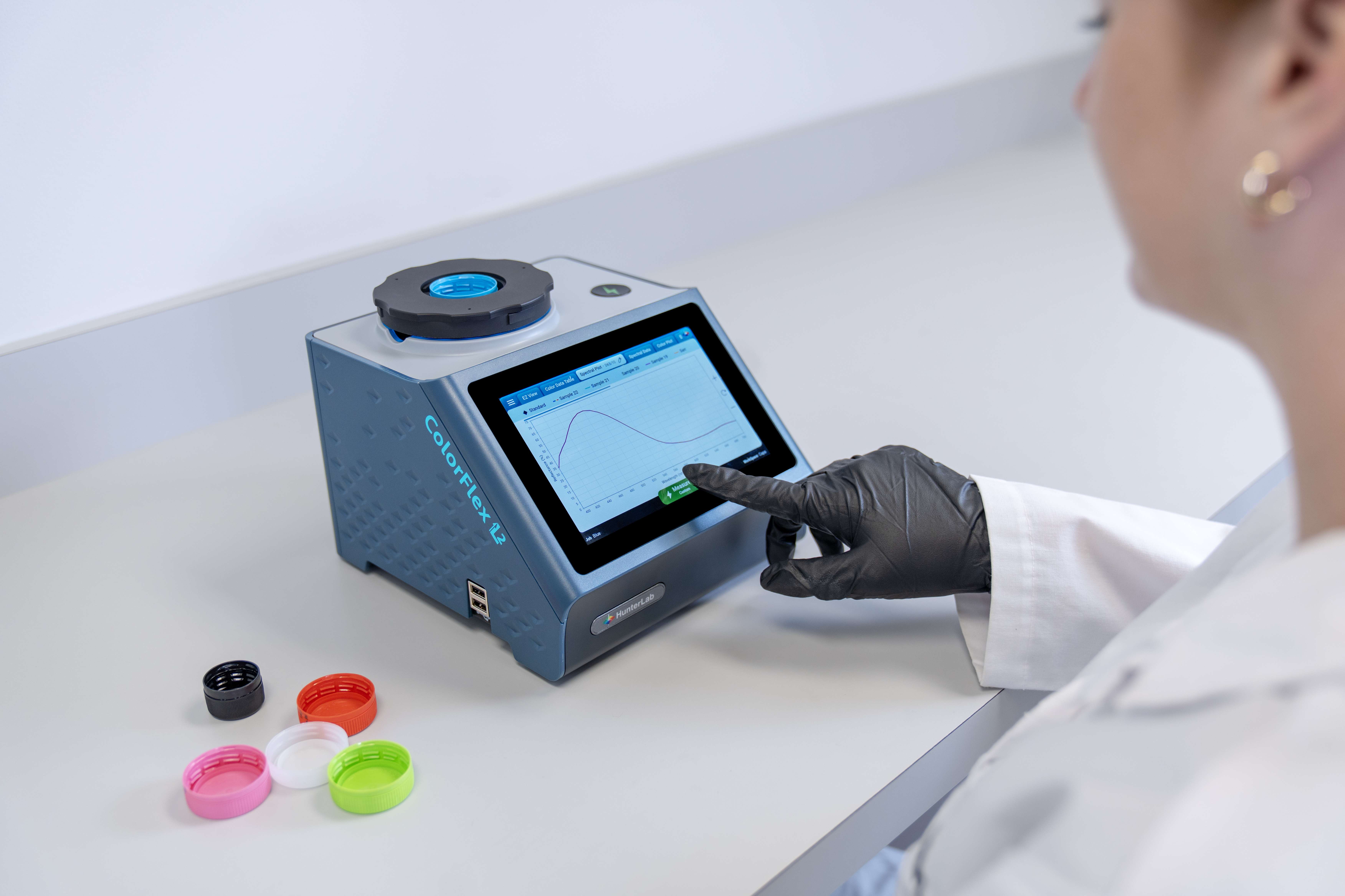 Technician using the ColorFlex L2 to measure the color of plastic caps
